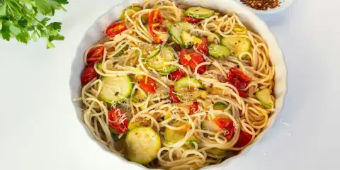 Pyszny makaron z cukinii, pomidorkami i parmezanem, gotowy do podania.