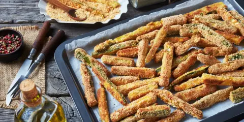 Fettine dorate di chips di zucchine pronte per essere gustate, su una teglia da forno.