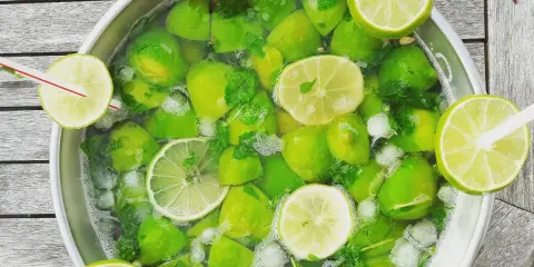 Un grand bol rempli de citrons verts, de menthe et de glaçons, prêt pour une recette mojito sans alcool 5 litres.
