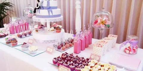 Mesa dulce para 50 cumpleaños con pastel de dos pisos, cupcakes, cake pops, bebidas rosas y palomitas.