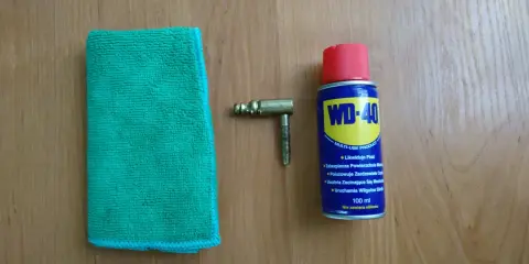 Ściereczka, mosiężny element i puszka WD-40 – wszystko gotowe do czyszczenia mosiądzu.