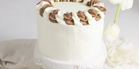 Tarta blanca con borde de nata y chocolate, lista para celebrar.