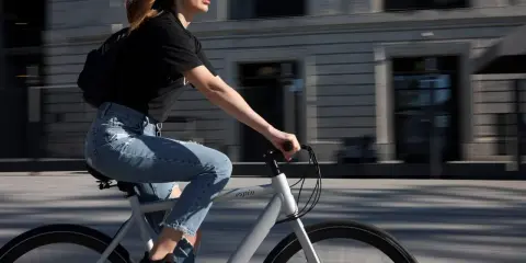 Kobieta w dżinsach i czarnej koszulce jedzie na rowerze. To dobry rower, idealny do miejskich podróży.