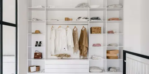 Idéal pour aménager un placard : étagères blanches remplies de vêtements, accessoires et boîtes.
