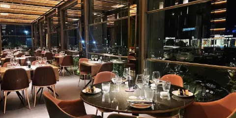 Interni eleganti del miglior ristorante di Rimini, con tavoli apparecchiati e vista notturna sulla città.