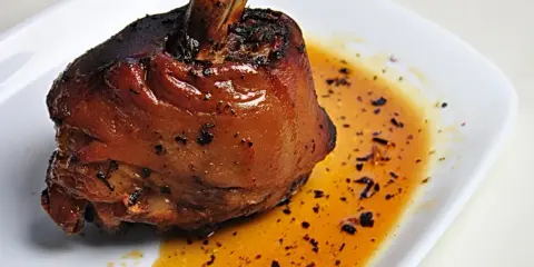 Apetyczna golonka w piwie, pieczona do perfekcji, z chrupiącą skórką i soczystym mięsem, podana w aromatycznym sosie.