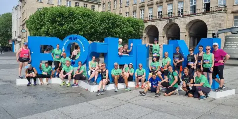 Gruppe feiert Erfolg beim urban run Bochum vor riesiger blauer Schrift.