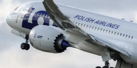 Samolot LOT Polish Airlines w locie, widok z boku na silnik i skrzydło.