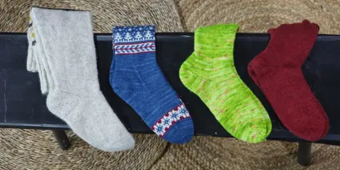 Fyra par handstickade sockor i olika färger och mönster. Perfekt för att sticka enkla sockor till barn.