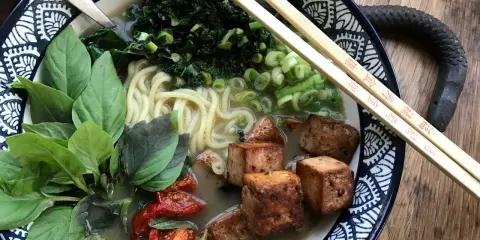 En skål med vegetarisk ramen med nudlar, tofu, grönsaker och basilika.