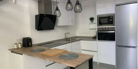 Cocina moderna con isla, electrodomésticos integrados y lámparas colgantes. Ideas para como diseñar una cocina funcional y elegante.