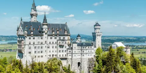 Märchenschloss Neuschwanstein, ein Meisterwerk romantischer Architektur, thront auf einem Felsen über einer malerischen Landschaft.