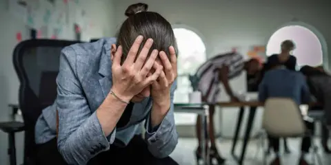 Personse tenant la tête entre les mains, visiblement stressée. Un test d'anxiété sociale pourrait révéler son état.