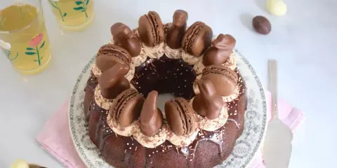 Gâteau rond au chocolat, décoré de macarons, de lapins en chocolat et d'une ganache carambar onctueuse.