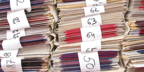 Stapel von Aktenordnern mit Nummern. Eine Frage, wie lange schulsachen aufbewahren, wird durch diese Archivierung thematisiert.