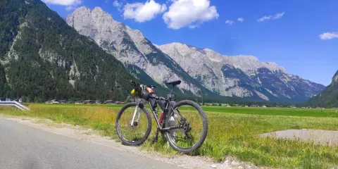 Rennrad für einen Alpencross, bereit für die Berge. Gepäcktaschen sind montiert, die Alpenkulisse ist atemberaubend.