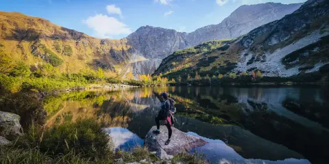 Widok na Rohackie wodospady i jezioro. Turystka podziwia jesienny krajobraz Tatr Zachodnich.