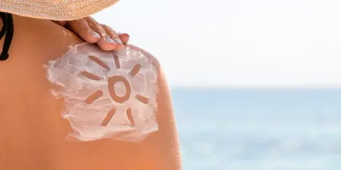Soleil dessiné sur l'épaule avec de la crème solaire. Attention au danger de la crème solaire tous les jours.