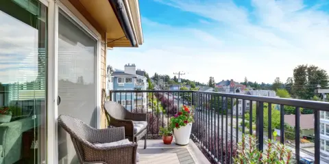 Wygodny balkon z rattanowymi meblami i kwiatami. Inspiracje na płytki na balkon.