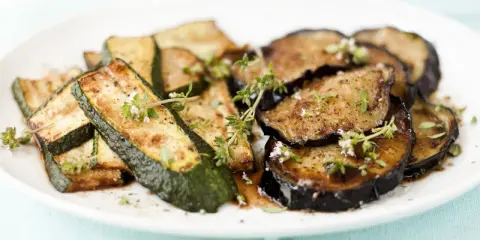 Gebratene Zucchini und Auberginen, italienisch gewürzt mit Kräutern, auf einem Teller.