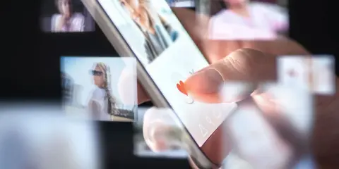 Palec przesuwa po ekranie smartfona, wybierając potencjalnych partnerów w aplikacjach randkowych.