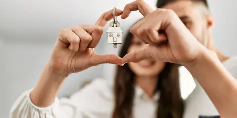 Un couple non marié célèbre son achat maison. Les mains forment un cœur autour de la clé, symbole de leur nouveau foyer, un nouveau départ après un décès.