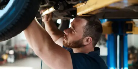 Mechanik sprawdza zawieszenie auta na podnośniku. Dowiedz się, ile kosztuje sprawdzenie zawieszenia na stacji diagnostycznej.