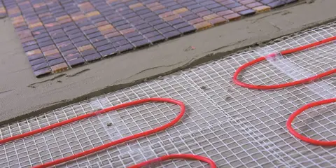 Układanie mozaiki na siatce z przewodami do ogrzewania podłogowego. Przewody ułożone co 10-15 cm zapewnią komfort cieplny.