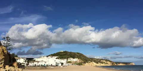 Sonne, Sand und weiße Häuser: Ein malerischer Blick auf Salema, Portugal, mit dem Atlantik und dramatischen Wolken.