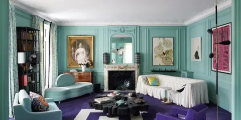 Sala de estar con paredes turquesas y alfombra morada. Muebles modernos y un retrato clásico crean un espacio amplio, ideal para aprender como pintar una habitacion para que se vea mas grande.