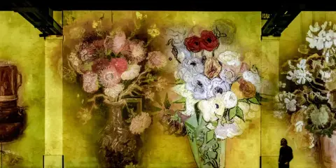 En person går förbi en väggprojektion av Van Goghs blomsterbuketter, en hyllning till hans tid i Paris.