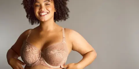 Donna sorridente con tette grandi perfette in reggiseno di pizzo color carne.