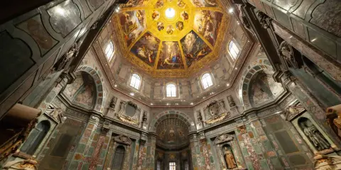 Intérieur de la Chapelle des Médicis, dôme orné de fresques dorées et de peintures religieuses, murs décorés de marbre et de sculptures.