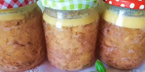 Trzy słoiki z domowym mięsem w galarecie, jak u babci. Na wierzchu warstwa tłuszczu, a na stole listki bazylii.