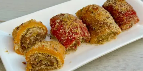 Involtini di peperoni ripieni e gratinati, serviti su un piatto bianco.