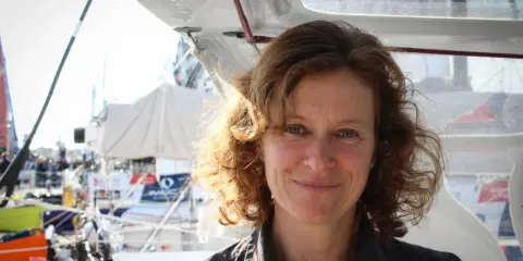Isabelle Joschke, souriante, sur un bateau, prête pour une nouvelle aventure maritime.