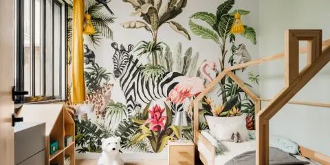 Une chambre d'enfant avec un mur jungle : zèbre, flamant rose, léopard, singe, toucan. Une excellente idée déco chambre enfant pour une aventure tropicale !