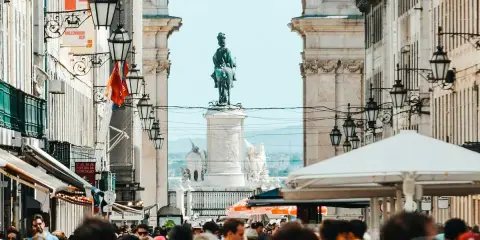 Menschenmenge auf der Rua Augusta in Lissabon mit Reiterstatue und Triumphbogen im Hintergrund.