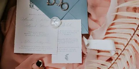 Eleganckie wypisywanie zaproszeń ślubnych z obrączkami i pieczęcią lakową.