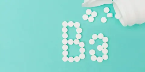 Des pilules blanches forment le "B3" sur fond turquoise. La vitamine B3, c'est quoi ? C'est essentiel pour votre corps.