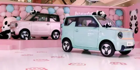 Due Geely Panda rosa e azzurra, circondate da palloncini e peluche di panda, in un allestimento a tema.