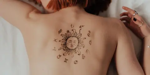 Tatuaż na plecach: słońce otoczone znakami zodiaku. Może symbolizuje ascendent w Lwie, emanujący energią i pewnością siebie.