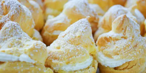 Une assiette de choux à la crème, saupoudrés de sucre glace. Ces petites merveilles de chou patisserie sont prêtes à être dégustées.
