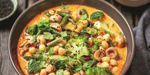 Kremowe curry z ciecierzycą, brokułami, fasolką szparagową i grzybami, posypane czarnym sezamem.