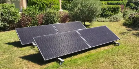 Panneaux solaires sur pelouse, promesse de rentabilité panneau solaire autoconsommation. Jardin verdoyant, maison en arrière-plan.