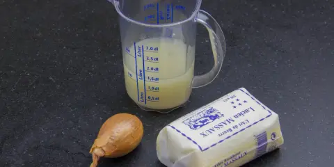 Ingrédients pour un beurre blanc : un oignon, un pichet gradué avec un liquide jaune, et un paquet de beurre Lucien Massaux.
