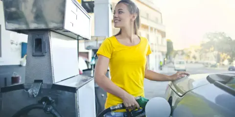 Uśmiechnięta dziewczyna tankuje auto, nalewając Vervę 98.