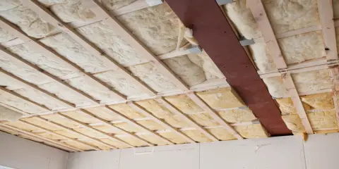 Holzlatten und eine Metallstrebe stützen die Dämmung. Glaswolle verarbeiten für eine gute Isolierung.