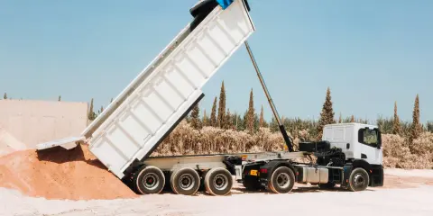Camión volquete descargando arena. La distancia entre ejes de los camiones es clave para su maniobrabilidad en terrenos difíciles.