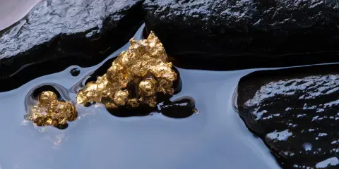 Oro grezzo, scintillante tra rocce scure e acqua limpida. Un'immagine che evoca il mistero di come nasce l'oro.